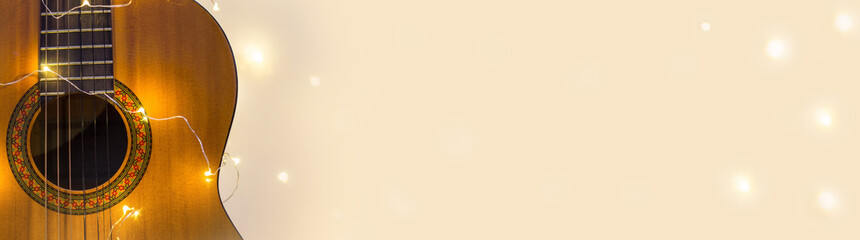 Obraz premium Banner of acoustic guitar wrapped in a luminous garland. Christmas gift