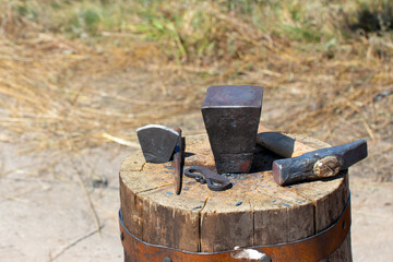 The old tools of a blacksmith on a large wooden stump