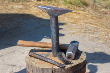 The old tools of a blacksmith on a large wooden stump
