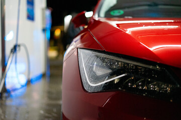 Closeup of the headlights of a red car.