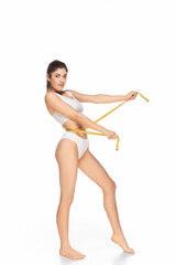 Tape measure. Beautiful female model on white background. Beauty, cosmetics, spa, depilation, diet and treatment, fitness concept. Fit and sportive, sensual body with well-kept skin in underwear.