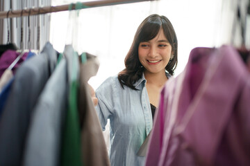 A portrait of a young woman entrepreneur in a clothing shop checking stock clothes