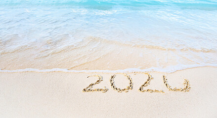 Year 2020 Written At The Sandy tropical Beach washing down with sea waves