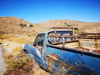 rusty old car wreck before mountain and desert panorama on the island of  Serifos, Greece
