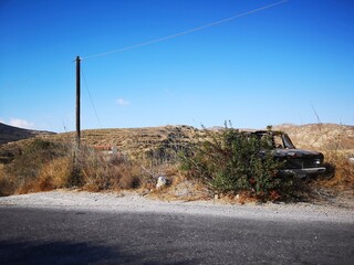 rusty old car before mountain and desert panorama opn the island of  Naxos, Greece