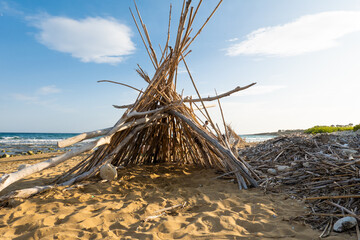 Tent like shelter of drift wood on empty beach, hide away, cast away stranded on island, traveling...