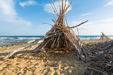 Tent like shelter of drift wood on empty beach, hide away, cast away stranded on island, traveling off the beaten track  © Ami