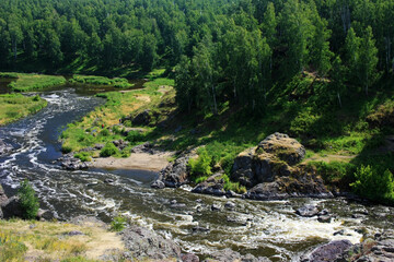 Fototapeta na wymiar Large stone boulders lie in a mountain river