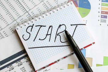 On the financial documents is a Notepad on which the word start is written. Business concept of new opportunities