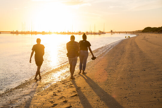 Group of friends walking at the beach during sunset