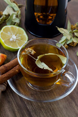 Dried linden tea cup on wooden table with French Press ,sliced apple,natural lemon and honey stick