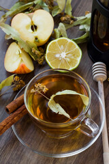 Dried linden tea cup on wooden table with French Press ,sliced apple,natural lemon and honey stick