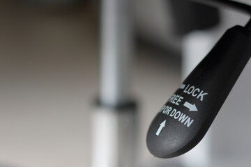 Closeup of black lever adjustable for lifting office chair mechanism.