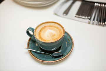 green coffee cup on table with forks and spoons