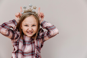 Funny portrait of a 10-year-old girl. the child shows horns. Emotional face.
