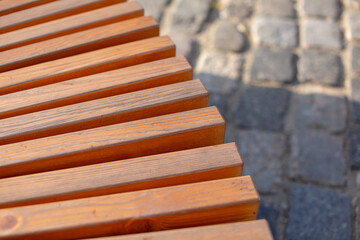 A wooden bench in the sun under it a stone path