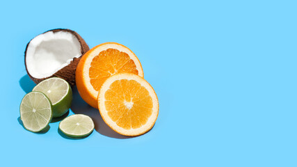 Fresh juicy orange, coconut and green lime isolated on blue background. Concept of Healthy eating and dieting. Travel and holiday concept