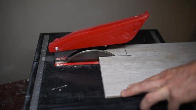  cut gray floor tiles with an electric tile cutter. cutting off a chipped tile