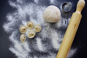 The process of making home-made dumplings. Raw homemade dumplings, dough, rolling pin and flour....