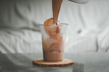 Pour cold Mocha coffee on ice ball in a plastic glass.