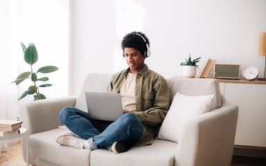 E-learning. African American teen student in headphones taking part in web conference or online...