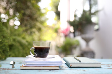 coffee in clear glass with spoon and notebook on blue wooden table
