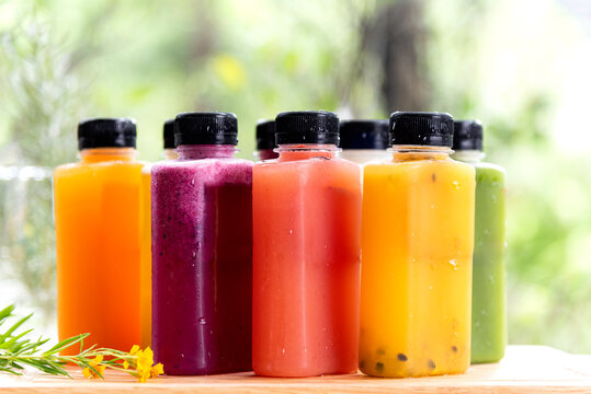 Freshly summer fruit and berries cold press juice serve in grass bottle in ther morning nature background.