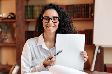 Young woman with glasses pointing to a sheet of paper