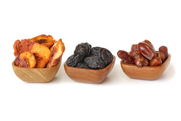 Dried peach, prune and dates in the wooden bowls isolated on white