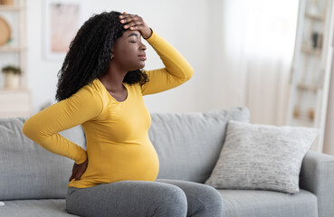 African american pregnant woman suffering from headache at home