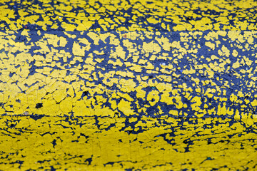 Background with close-up of yellow paint flaking off a black wet plastic part of a road boundary. Seen in Germany in October.