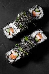 Vertical frame, set of 8 rolls with salmon, cucumber and shrimp on a black stone board