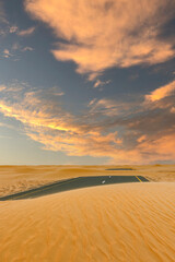 (Selective focus) Stunning view of a deserted road covered by sand dunes running through the Dubai desert. Dubai, United Arab Emirates, (UEA).