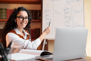 English teacher sitting at table, explaining lesson to students