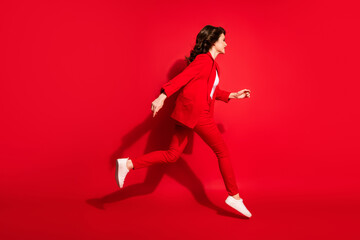 Full length profile photo of charming young girl fast running wear blazer pants footwear isolated red color background