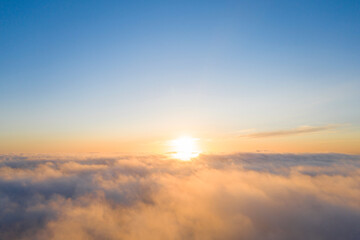 Obraz premium Aerial view gold sunrise over clouds in blue sky. Aerial top view cloudscape. Texture of clouds. View from above. Orange sunrise or sunset over clouds. Panorama clouds texture