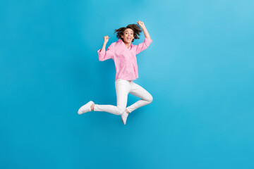 Obraz premium Full size photo of ecstatic girl jump raise fists wear formal clothes sneakers isolated over blue color background