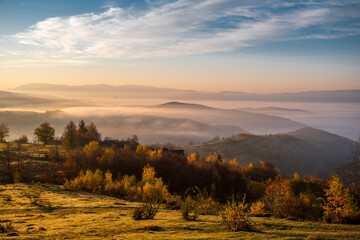 dawn green glade on a background of mountains in the fog the sky shimmers with beautiful colors. Autumn season.