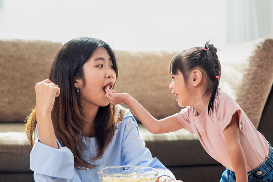 Happy Asian Child Enjoy Eating Popcorn With Her Older Sister