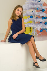 Girl in Stylish Dress Sitting on the Floor in Front of Christmas Tree