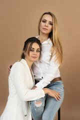 Portrait of two smiling young women models on a beige background