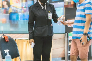 Hand of customer waits for a drop of alcohol gel from female security guard to prevent the spread of germs and bacteria and avoid infections Corona virus (Covid-19) before entering the mall.