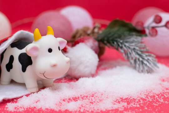 Decorations for the new year, postcard design. Toy bull in a santa hat, new year garland, snow. A photo