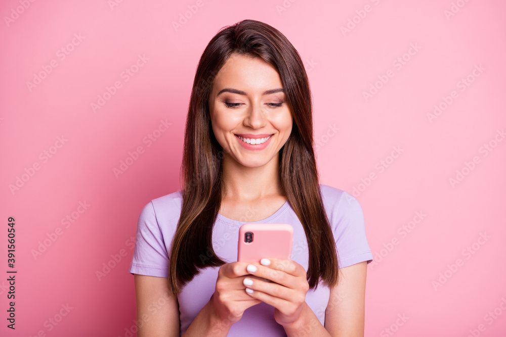 Sticker Photo portrait of girl holding phone in two hands isolated on pastel pink colored background