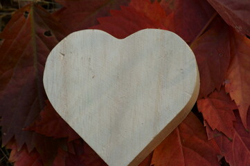 Wooden heart on the background of autumn leaves.