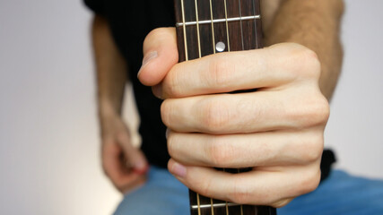 Close-up of a mans hand holding a guitar fretboard