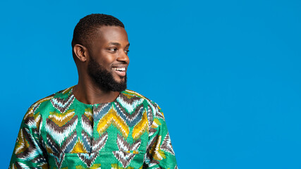Positive black man in african shirt looking at copy space