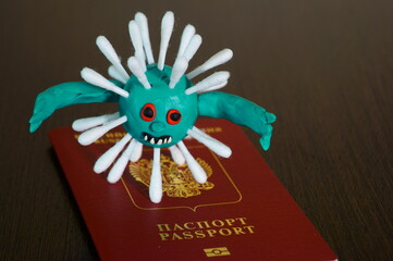 Figure of a virus made of plasticine next to the passport.