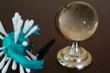 The figure of the virus with a toy gun. Next to it is a small glass globe.