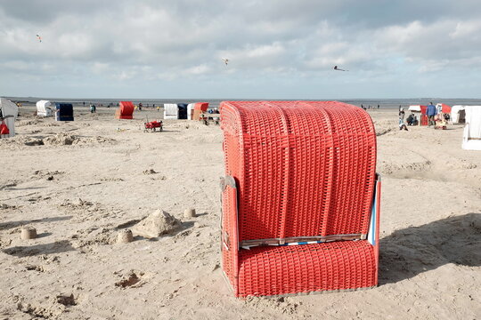 Roter Strandkorb am Strand von Bensersiel im Herbst bei Sonnenschein an der K&uuml;ste der Nordsee bei Esens in Ostfriesland in Niedersachsen